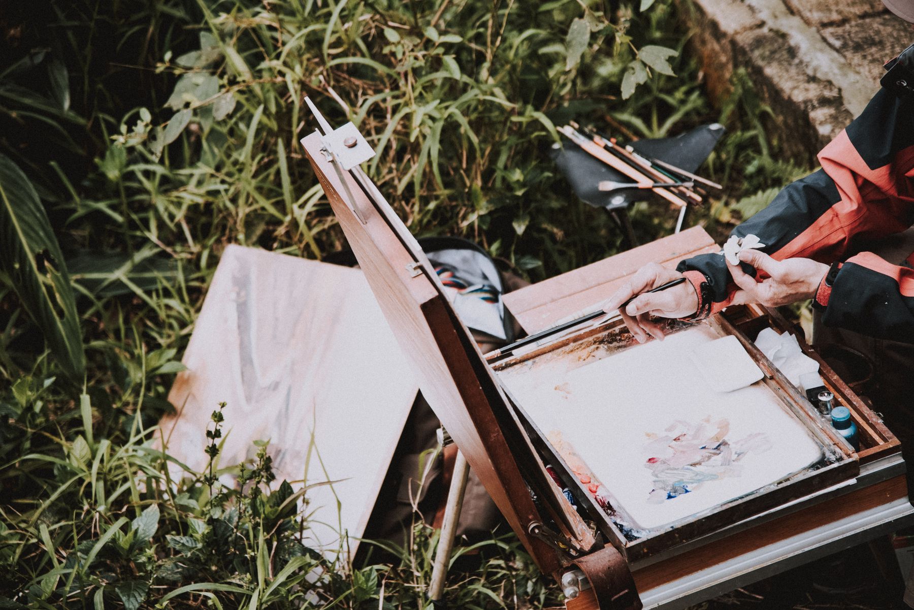 A painter's easel set up outdoors among tall grass